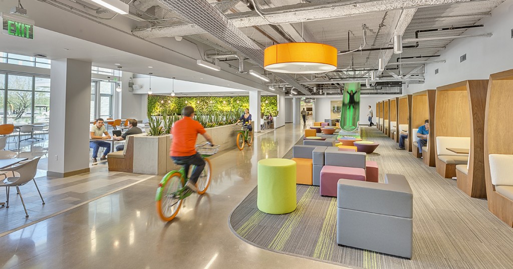 Ufficio moderno open space con persone che si spostano in bicicletta